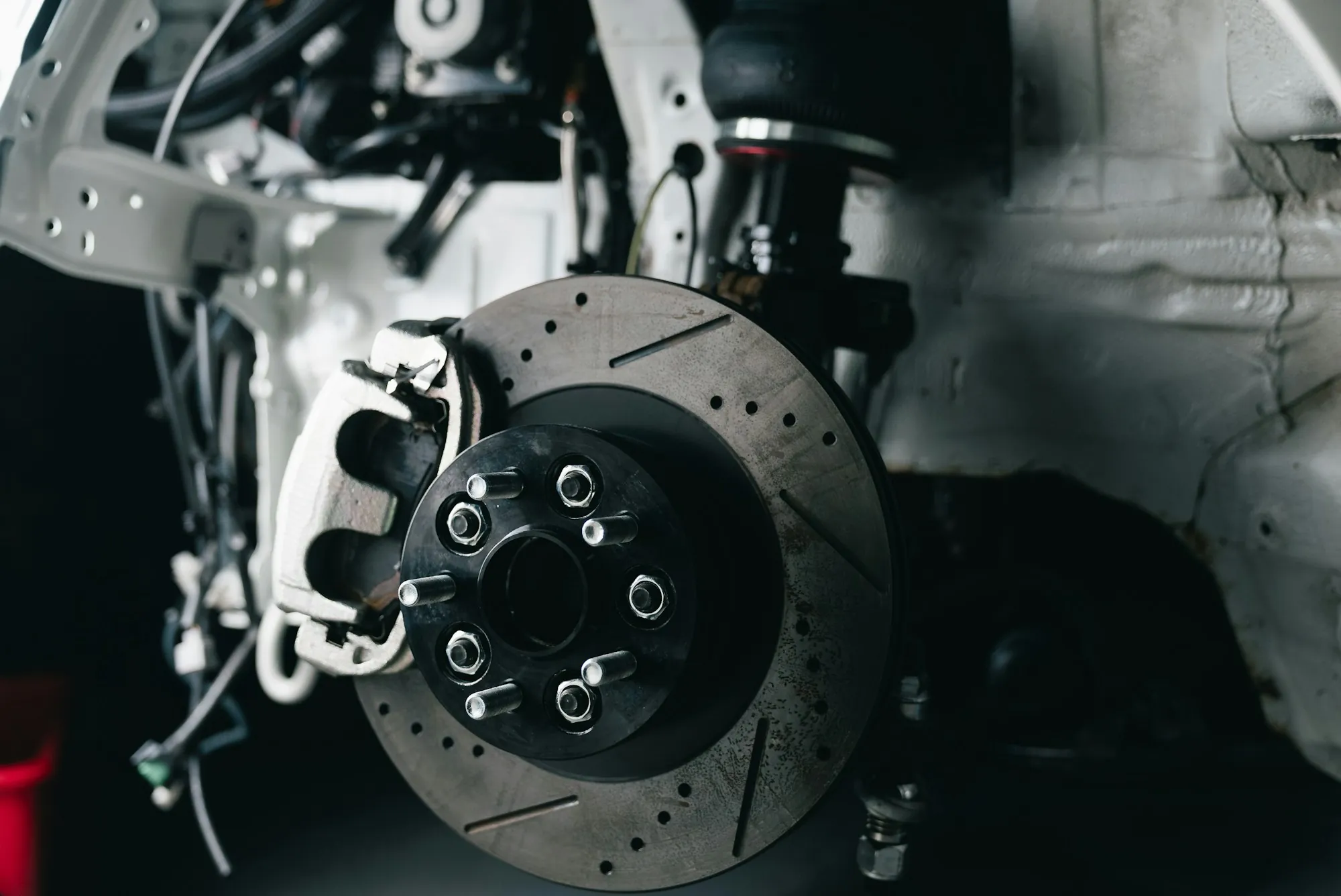 Brake rotor and caliper visible on a vehicle in the shop