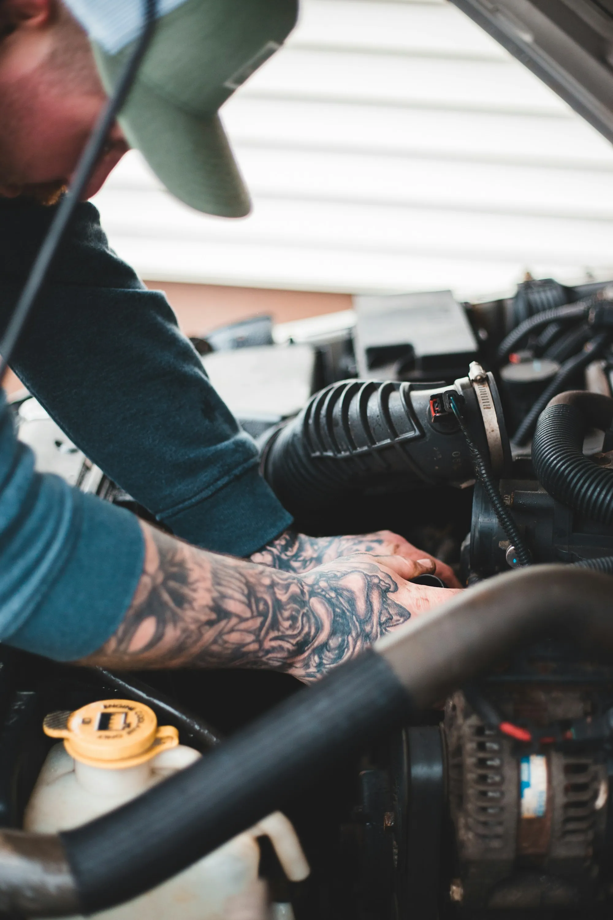 Technician with tattooed arms working in an engine bay
